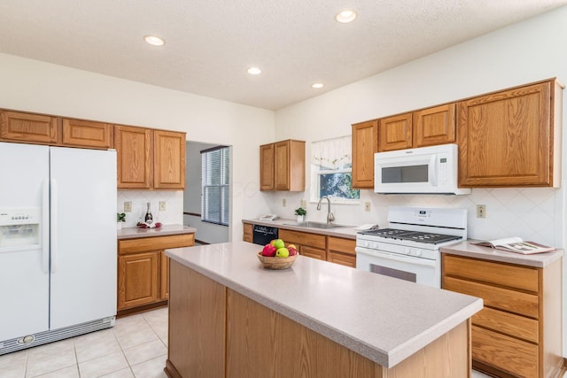 kitchen featuring white appliances, a kitchen island, brown cabinets, light countertops, and a sink