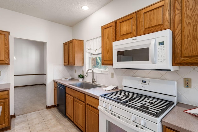 kitchen with a textured ceiling, white appliances, a sink, tasteful backsplash, and brown cabinetry