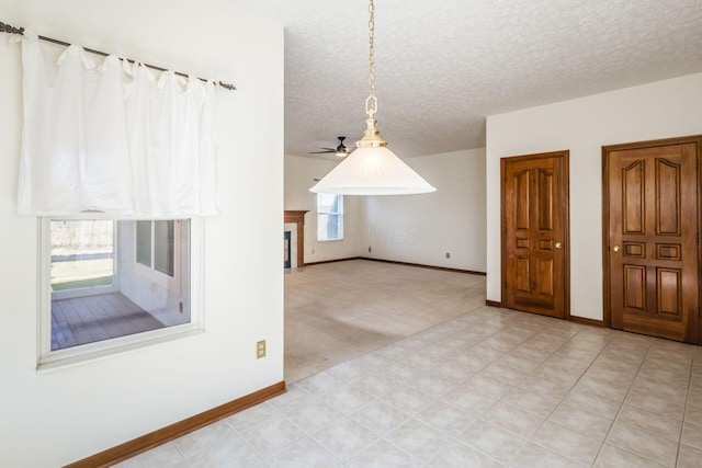 bonus room featuring a textured ceiling, a glass covered fireplace, a wealth of natural light, and baseboards