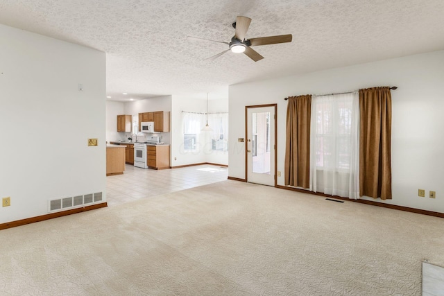 unfurnished living room with a ceiling fan, light carpet, visible vents, and a textured ceiling