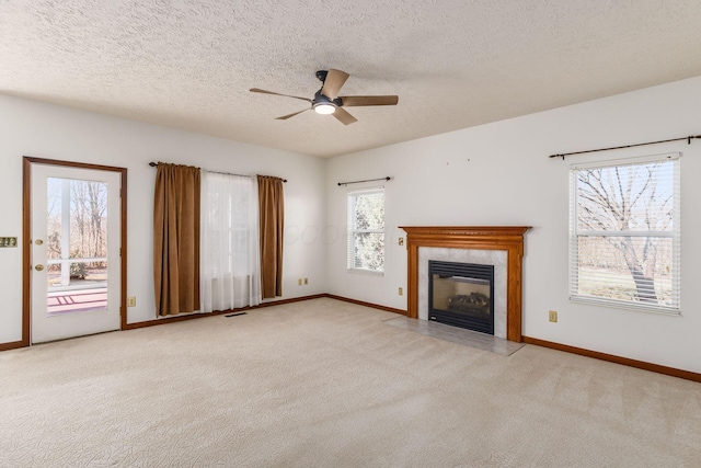 unfurnished living room with carpet floors, baseboards, visible vents, and a tiled fireplace