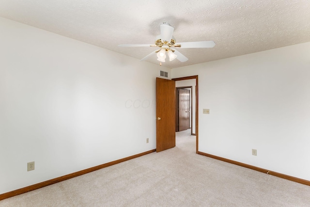 spare room with light colored carpet, visible vents, ceiling fan, a textured ceiling, and baseboards