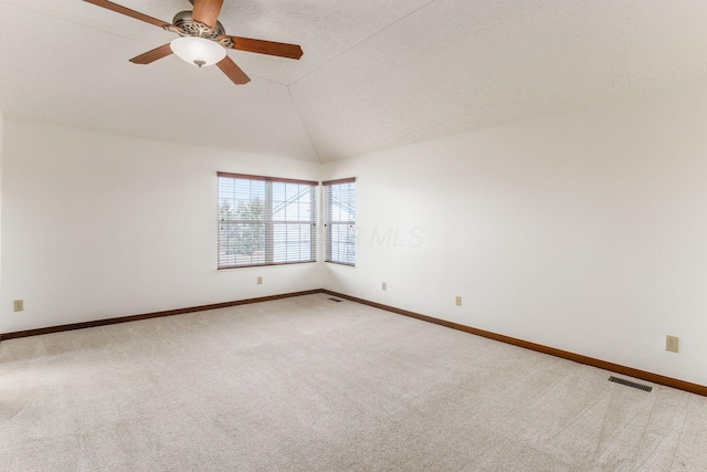 carpeted spare room with lofted ceiling, ceiling fan, visible vents, and baseboards