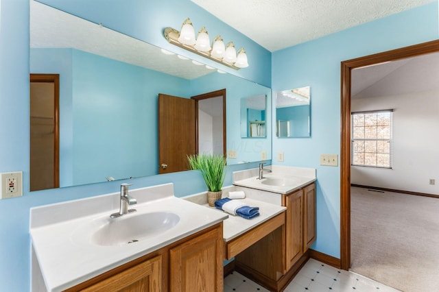 bathroom with a textured ceiling, double vanity, a sink, and baseboards