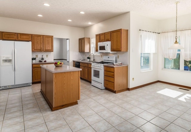 kitchen with white appliances, a sink, visible vents, light countertops, and brown cabinets