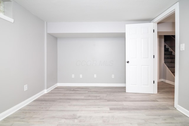 interior space featuring wood finished floors, baseboards, and stairway