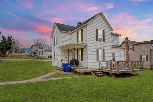 back of property at dusk featuring a yard, a chimney, and a wooden deck