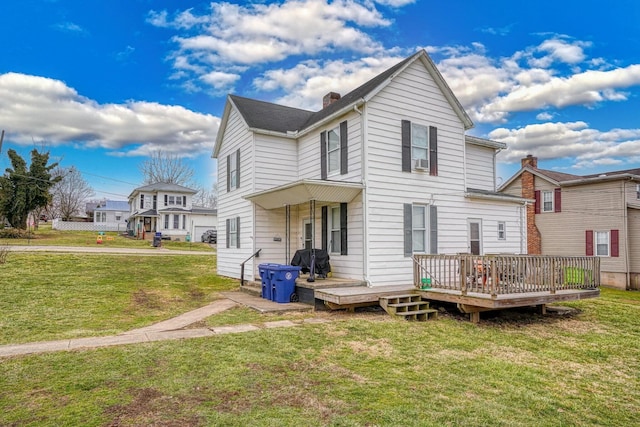 back of property with a chimney, a lawn, and a deck