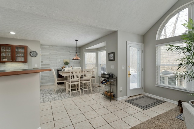 entryway with light tile patterned floors, baseboards, vaulted ceiling, and a textured ceiling