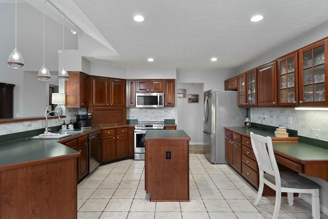 kitchen with dark countertops, appliances with stainless steel finishes, a sink, and a center island