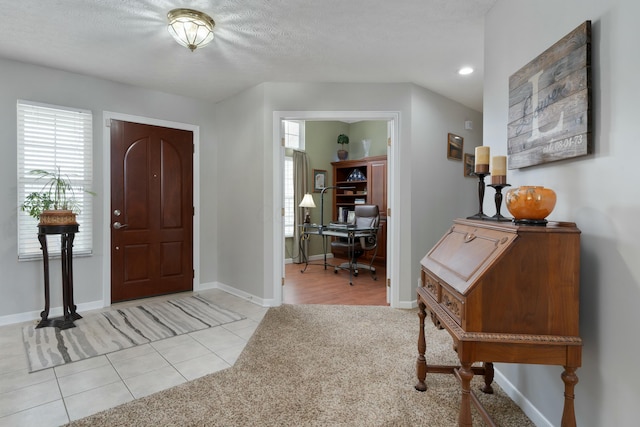 entrance foyer with plenty of natural light, light colored carpet, light tile patterned flooring, and baseboards