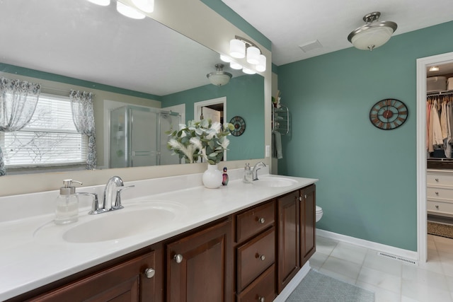 bathroom featuring a sink, a shower stall, baseboards, and double vanity