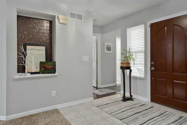 entryway featuring a healthy amount of sunlight, visible vents, baseboards, and light tile patterned flooring