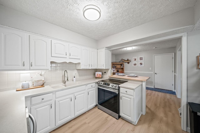 kitchen with light wood-style floors, white cabinets, a sink, and stainless steel electric range