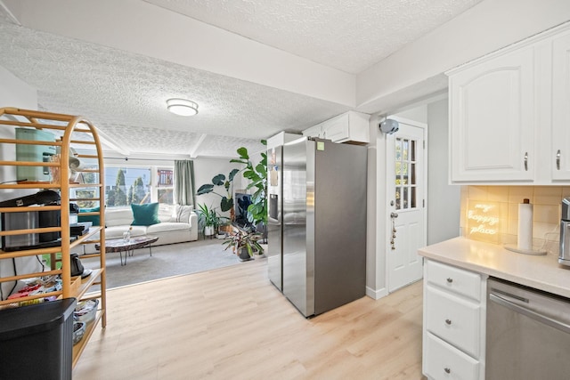 kitchen with light wood finished floors, appliances with stainless steel finishes, plenty of natural light, and backsplash