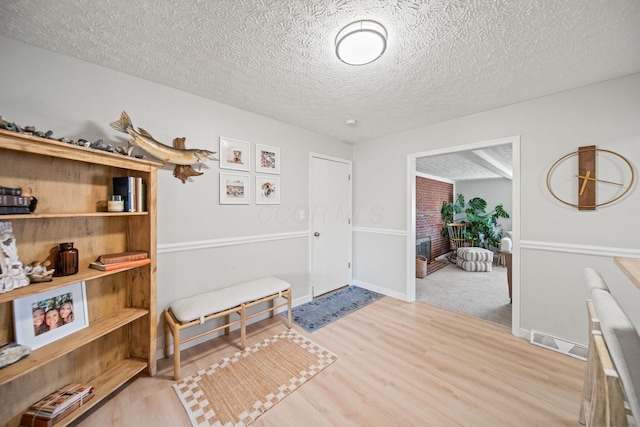 interior space featuring a textured ceiling, wood finished floors, and baseboards