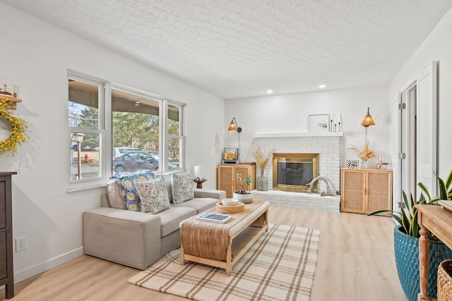 living room featuring a textured ceiling, recessed lighting, a fireplace, wood finished floors, and baseboards