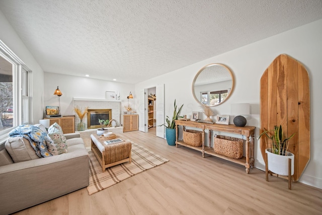 living area featuring a brick fireplace, a textured ceiling, and wood finished floors