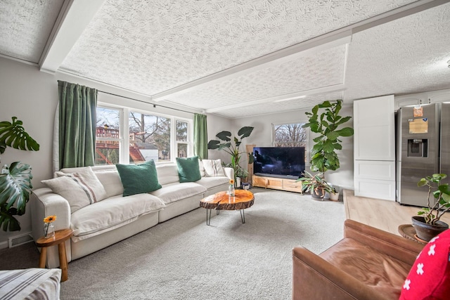 living area with a textured ceiling, plenty of natural light, wood finished floors, and visible vents