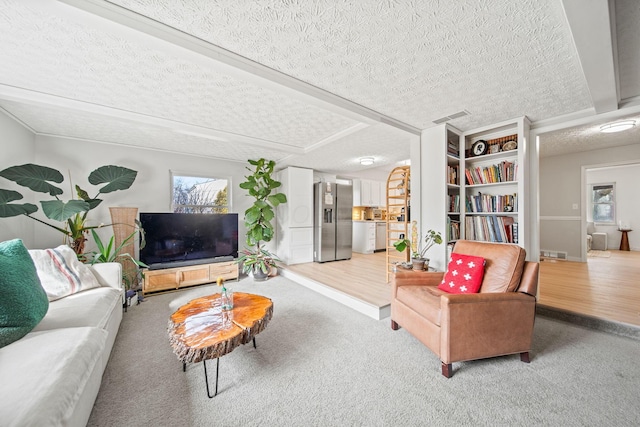 living room featuring light carpet, light wood-style floors, visible vents, and a textured ceiling