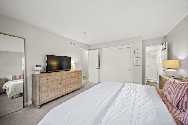 bedroom with light carpet, visible vents, a closet, and ensuite bathroom