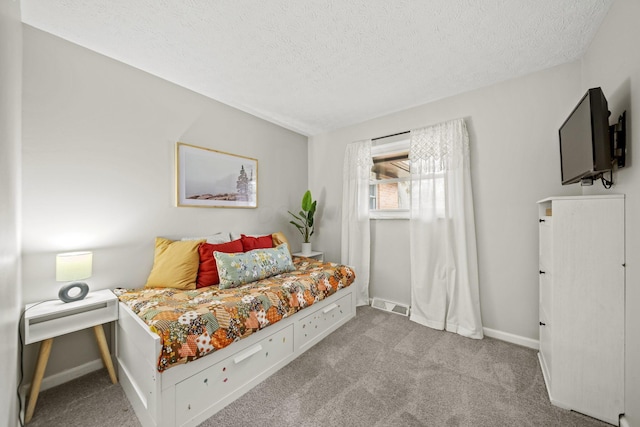 bedroom with baseboards, a textured ceiling, visible vents, and carpet flooring