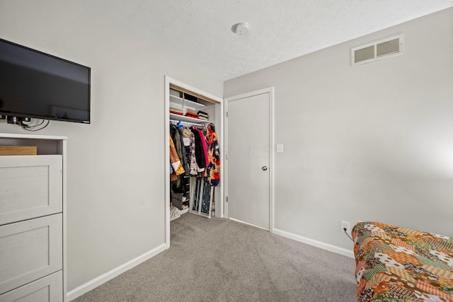 unfurnished bedroom featuring a closet, visible vents, carpet flooring, a textured ceiling, and baseboards