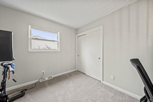 unfurnished office featuring a textured ceiling, carpet floors, visible vents, and baseboards