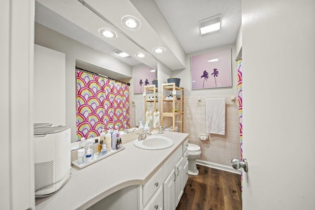 full bath featuring a wainscoted wall, tile walls, toilet, vanity, and wood finished floors