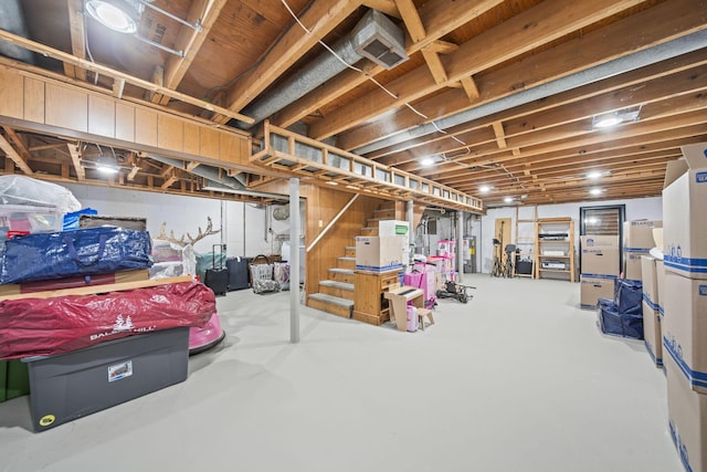 unfinished basement with water heater and stairway