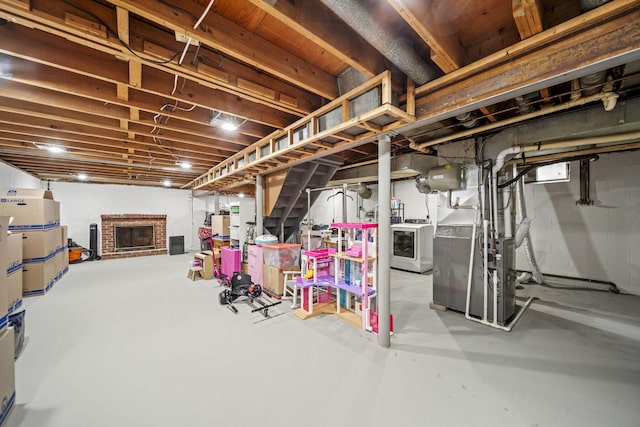 unfinished below grade area featuring a brick fireplace, heating unit, and washing machine and clothes dryer