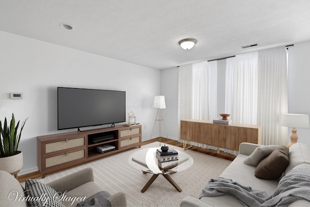 living room with baseboards, visible vents, and wood finished floors