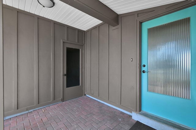 view of exterior entry featuring board and batten siding and a patio area