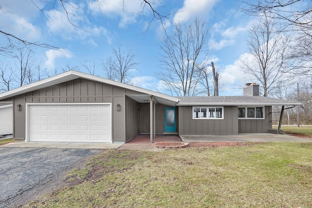 view of front of house featuring a garage, driveway, board and batten siding, a front lawn, and a chimney