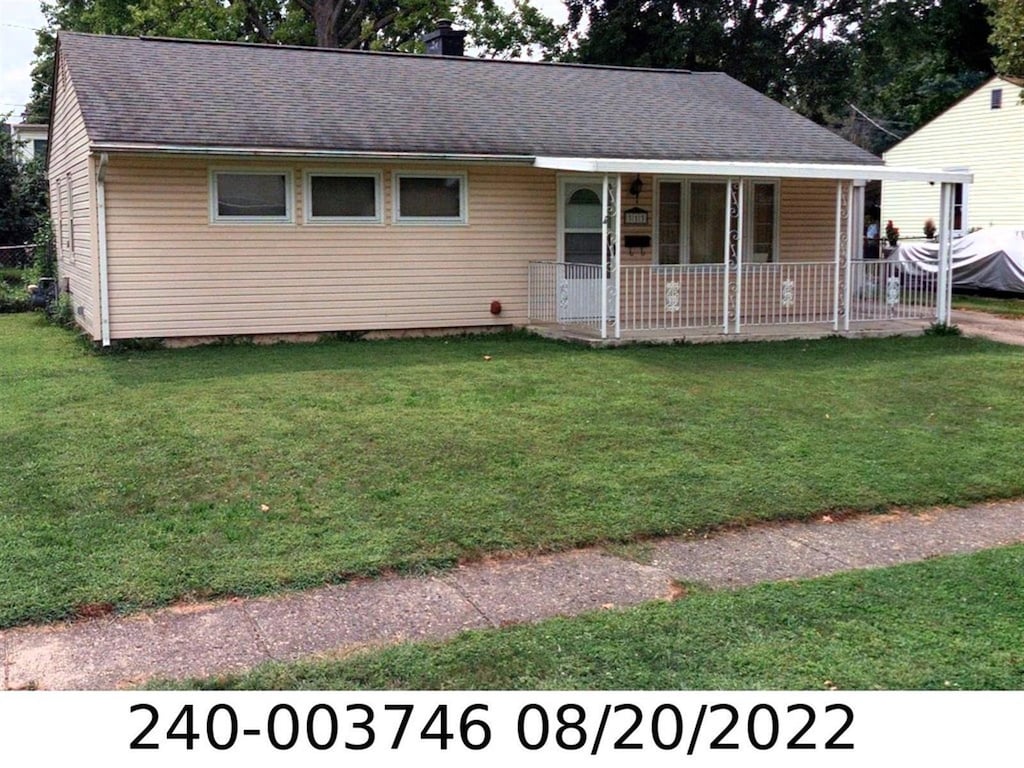 ranch-style house with a porch, a front yard, roof with shingles, and a chimney