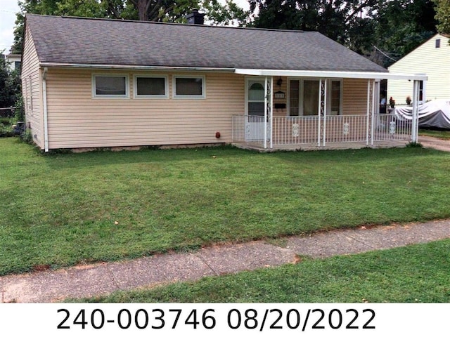 ranch-style house with a porch, a front yard, roof with shingles, and a chimney