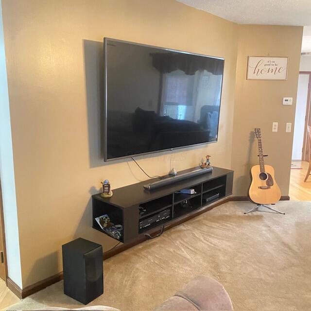 carpeted living room featuring a textured ceiling and baseboards