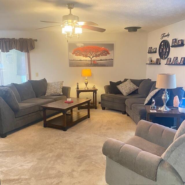 living room featuring light carpet, ceiling fan, and a textured ceiling