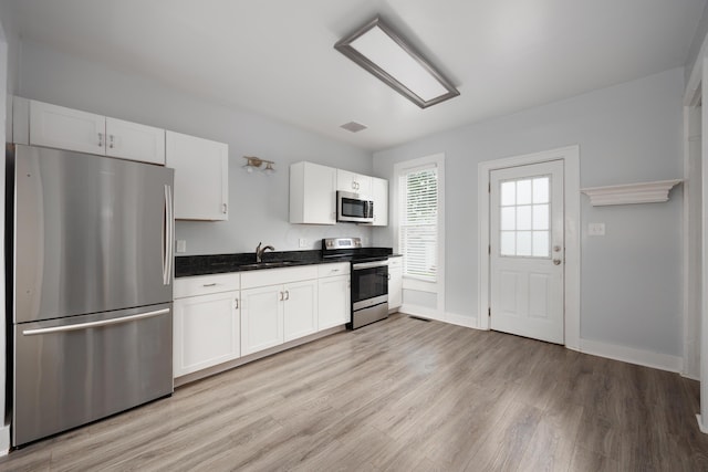 409 High St, Utica, OH 43080 - kitchen with stainless steel appliances, light wood-style floors, dark countertops, and white cabinets