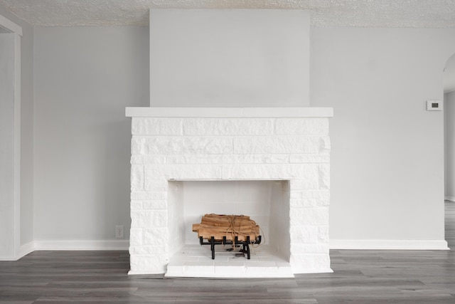 room details featuring arched walkways, a fireplace, a textured ceiling, wood finished floors, and baseboards