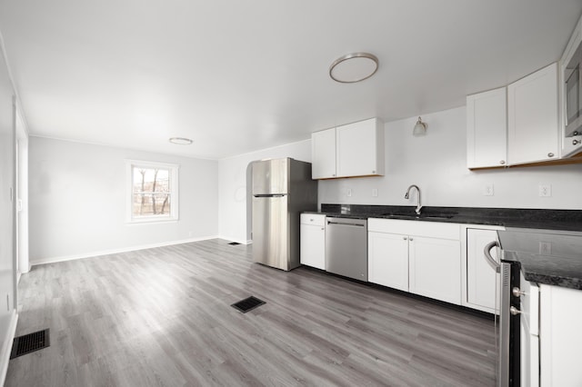 kitchen with visible vents, light wood-style flooring, appliances with stainless steel finishes, white cabinetry, and a sink