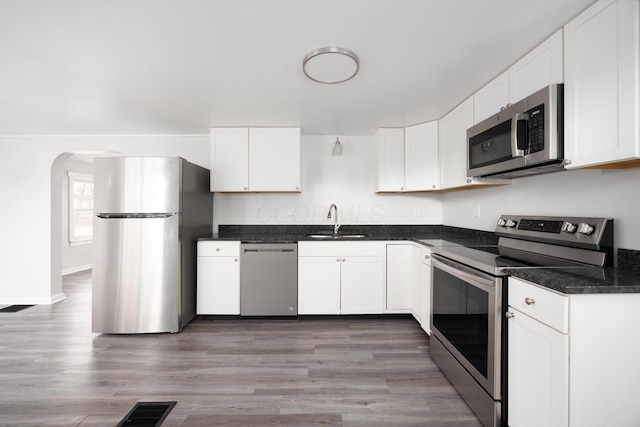 kitchen with visible vents, light wood-style flooring, stainless steel appliances, white cabinetry, and a sink