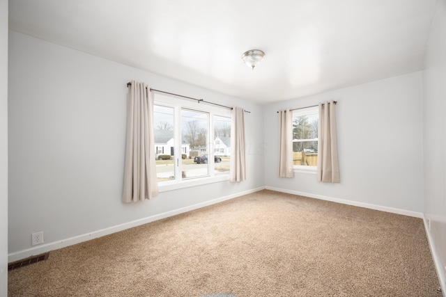 carpeted empty room featuring baseboards and visible vents