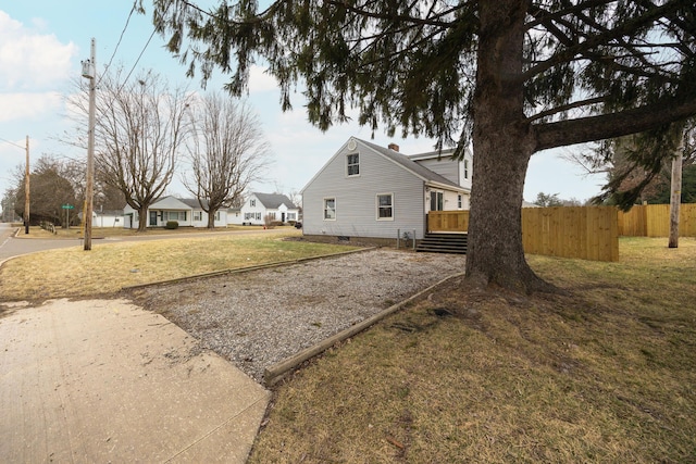 view of home's exterior featuring fence, a deck, and a lawn