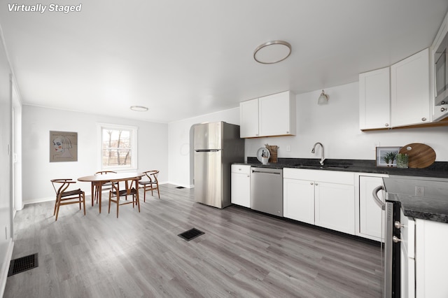 kitchen featuring white cabinets, visible vents, stainless steel appliances, and a sink