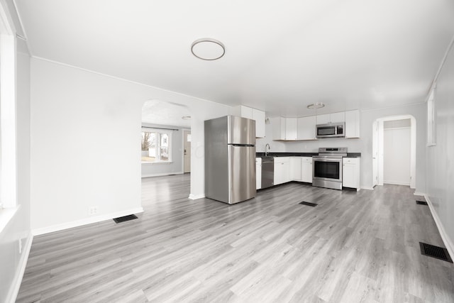 kitchen featuring arched walkways, stainless steel appliances, and visible vents