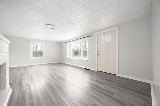 unfurnished living room featuring a wealth of natural light, visible vents, and wood finished floors