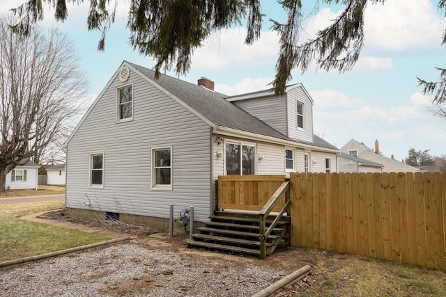 back of house featuring roof with shingles, a chimney, and fence