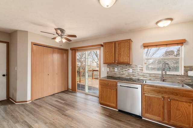 kitchen featuring dark countertops, brown cabinets, dishwasher, and a sink