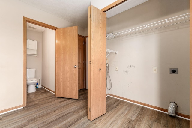 laundry room featuring baseboards, hookup for an electric dryer, light wood finished floors, and laundry area